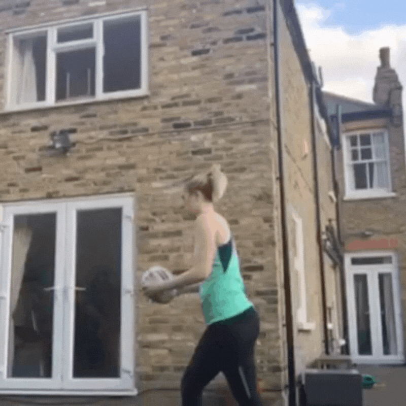 Ram Rugby Solo Skills Ball shown in mid-air against a wall, designed for solo rugby passing practice and rebound training